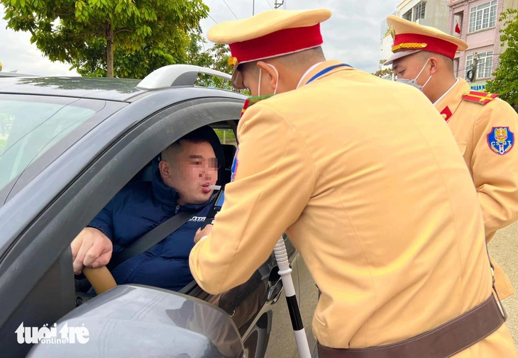 Cảnh sát giao thông kiểm tra nồng độ cồn với tài xế lái ô tô - Ảnh: DANH TRỌNG